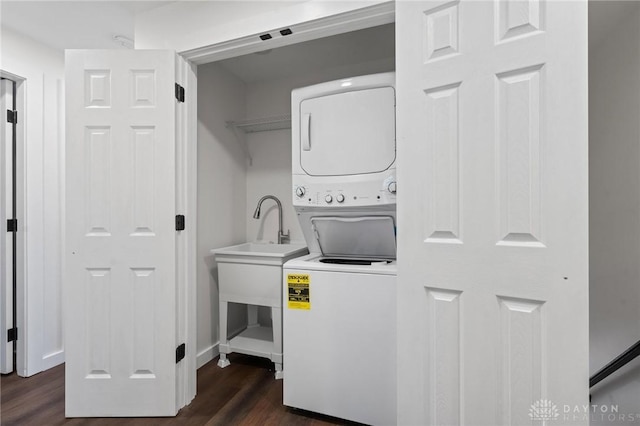 laundry room with stacked washer and dryer and dark wood-type flooring