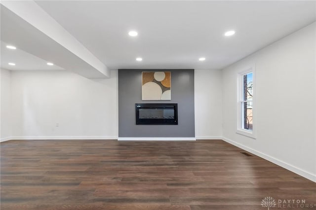 unfurnished living room featuring a large fireplace and dark hardwood / wood-style floors