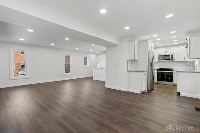 interior space with appliances with stainless steel finishes, dark hardwood / wood-style flooring, tasteful backsplash, sink, and white cabinetry