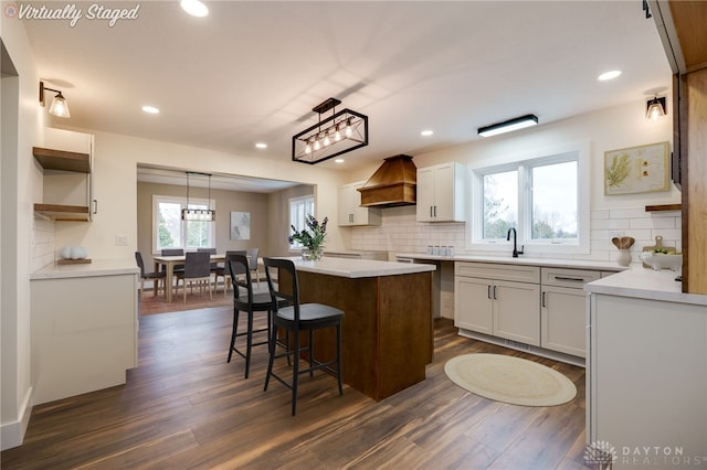 kitchen featuring pendant lighting, a center island, premium range hood, white cabinets, and dark hardwood / wood-style floors