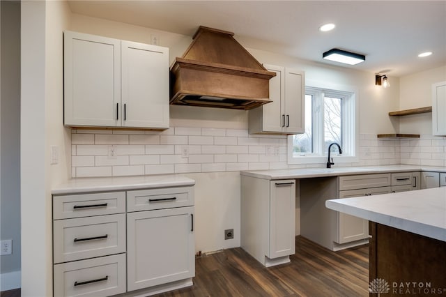 kitchen with dark hardwood / wood-style flooring, tasteful backsplash, custom range hood, sink, and white cabinetry