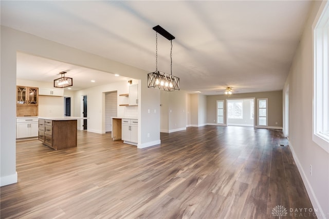 kitchen with hardwood / wood-style floors, backsplash, ceiling fan, decorative light fixtures, and white cabinetry