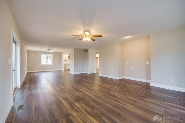 unfurnished room with ceiling fan with notable chandelier and dark hardwood / wood-style floors