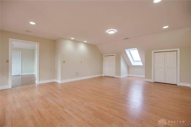 bonus room featuring vaulted ceiling with skylight and light hardwood / wood-style flooring