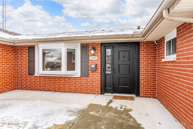 snow covered property entrance with a patio