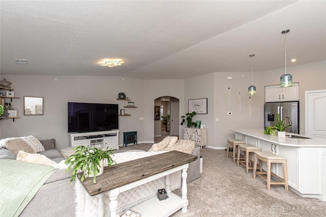 living room featuring a textured ceiling, light colored carpet, and sink