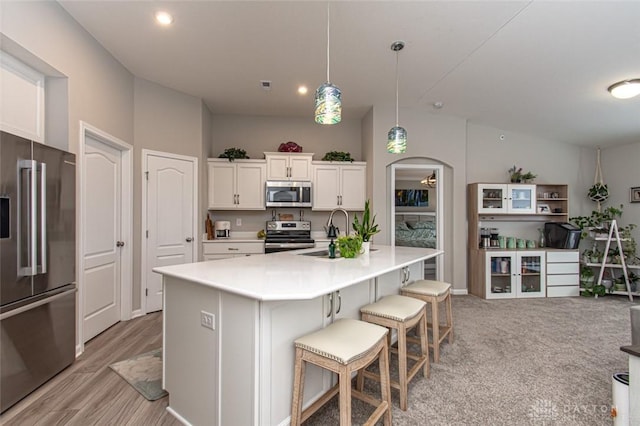 kitchen featuring appliances with stainless steel finishes, sink, pendant lighting, white cabinets, and an island with sink