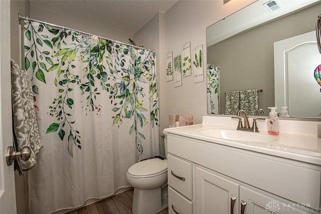 bathroom featuring vanity, toilet, wood-type flooring, and walk in shower