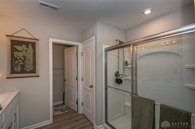 bathroom featuring wood-type flooring, vanity, and walk in shower