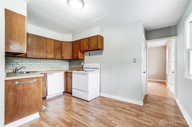 kitchen with decorative backsplash, light hardwood / wood-style floors, white appliances, and sink