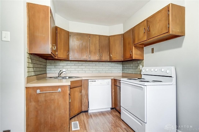 kitchen featuring tasteful backsplash, sink, white appliances, and light hardwood / wood-style flooring