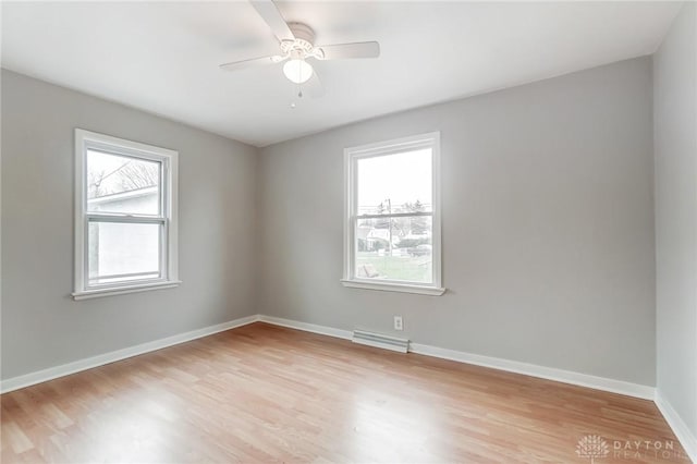 empty room featuring ceiling fan, plenty of natural light, and light hardwood / wood-style floors