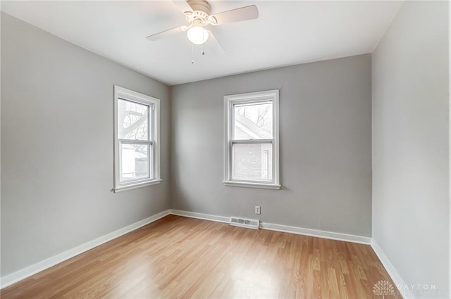 spare room featuring ceiling fan, a healthy amount of sunlight, and light wood-type flooring