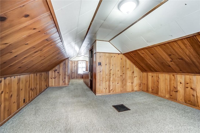 bonus room with light carpet, vaulted ceiling, and wooden walls