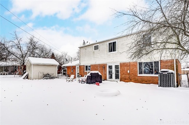 snow covered property with central AC and french doors