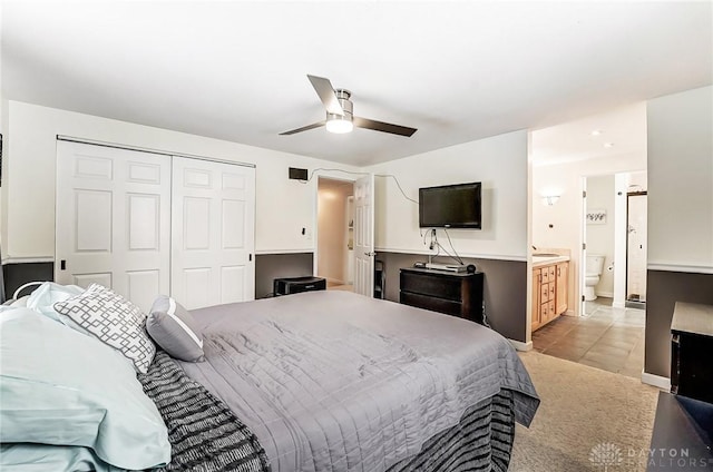 bedroom with light tile patterned floors, ensuite bath, a closet, and ceiling fan