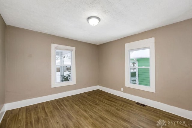 empty room with dark wood-type flooring and a textured ceiling