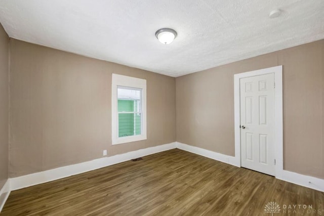 empty room featuring dark hardwood / wood-style flooring and a textured ceiling