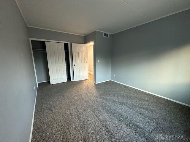 unfurnished bedroom with dark carpet and a closet