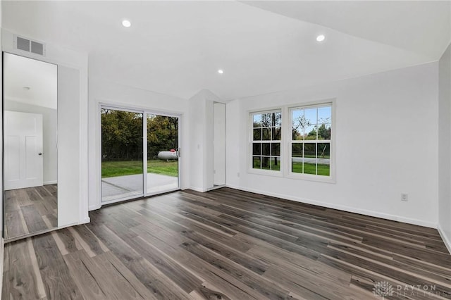 empty room with dark wood-type flooring, a wealth of natural light, and lofted ceiling