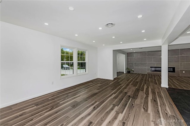 unfurnished living room with dark hardwood / wood-style flooring and a tiled fireplace