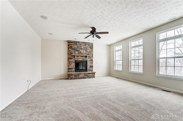 unfurnished living room featuring a fireplace, a textured ceiling, light colored carpet, and ceiling fan