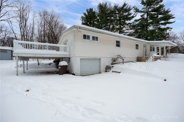 snow covered back of property featuring a garage