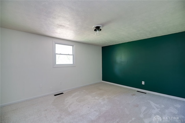 spare room featuring a textured ceiling, carpet, and baseboards