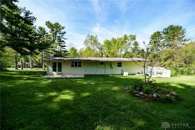back of property with a lawn and a patio