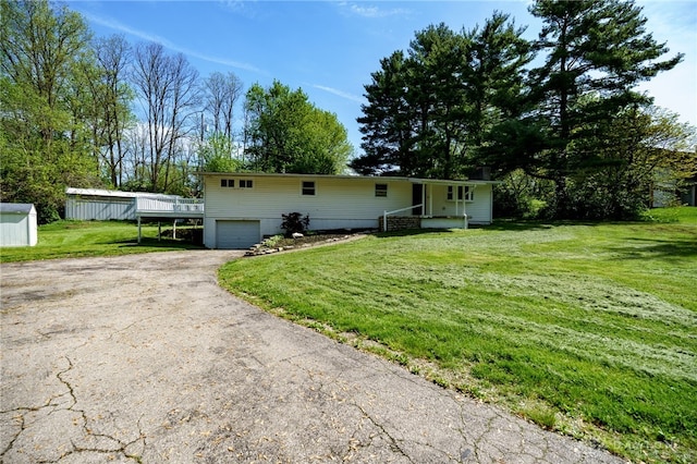 view of front of home featuring asphalt driveway, an attached garage, and a front yard