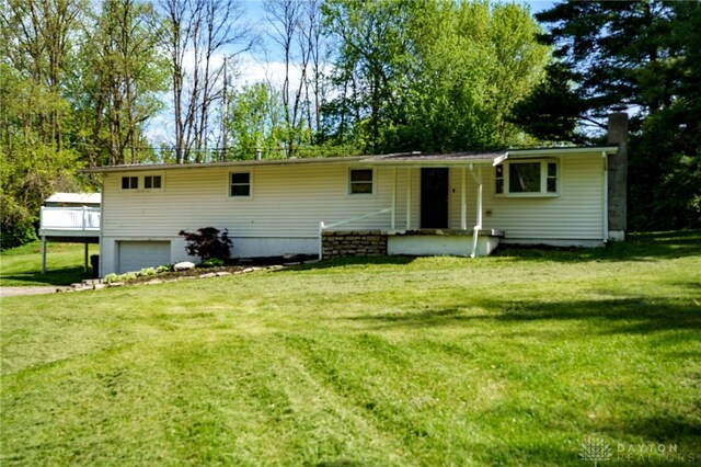 back of house with an attached garage, a yard, and driveway