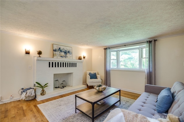 living area featuring a textured ceiling, a fireplace, ornamental molding, wood finished floors, and baseboards
