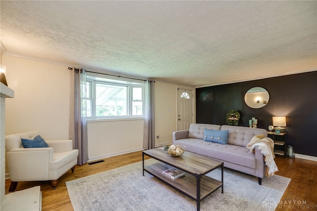 living room featuring a textured ceiling, wood finished floors, ornamental molding, and baseboards