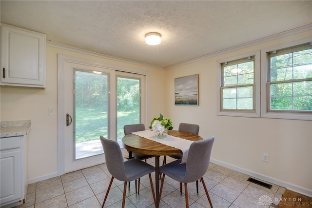 dining area with healthy amount of natural light, a textured ceiling, baseboards, crown molding, and light tile patterned floors