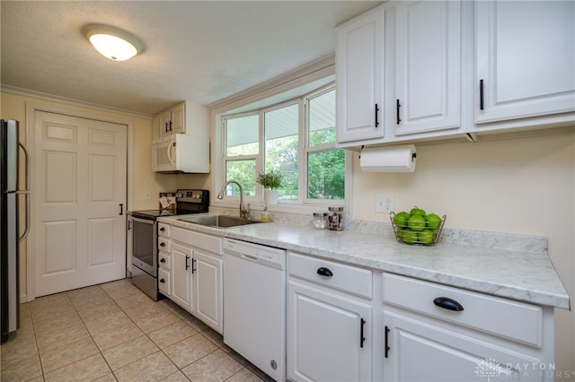 kitchen with white appliances, a sink, white cabinets, light tile patterned flooring, and a textured ceiling
