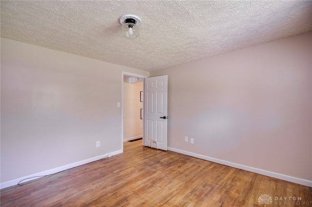 empty room with baseboards, light wood-style flooring, and a textured ceiling