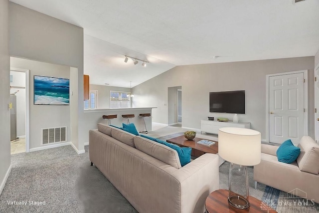 carpeted living room featuring track lighting and vaulted ceiling