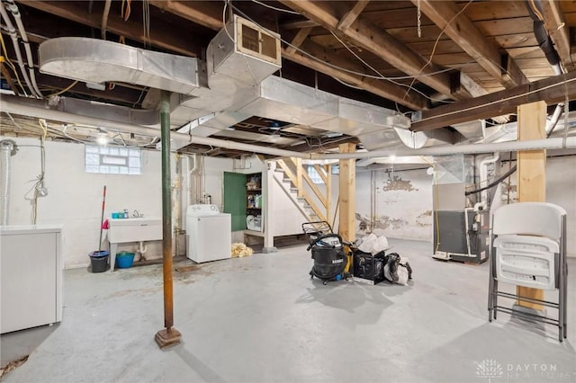 basement featuring heating unit, separate washer and dryer, and sink