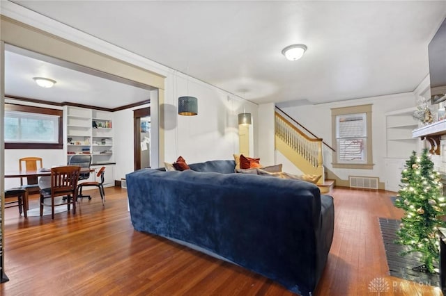 living room featuring dark hardwood / wood-style floors, built in features, and ornamental molding