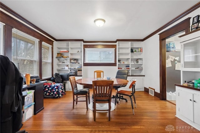 dining area featuring wood-type flooring and ornamental molding