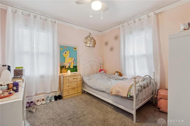 carpeted bedroom featuring multiple windows and ceiling fan