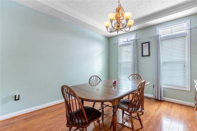 dining room with a chandelier, light wood-type flooring, and a textured ceiling