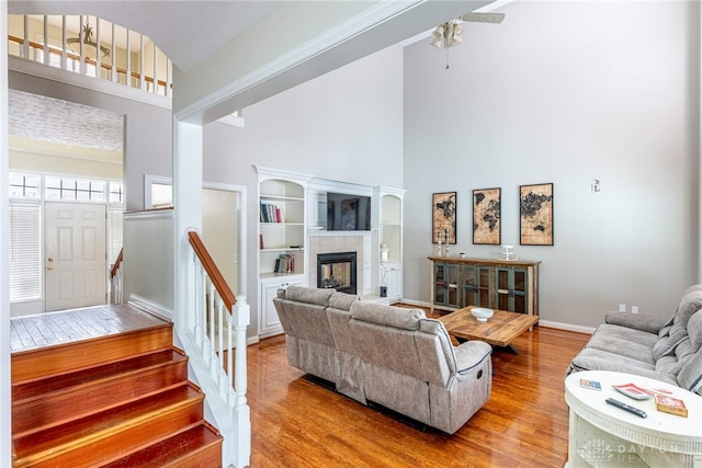 living room with hardwood / wood-style flooring, ceiling fan, a fireplace, and high vaulted ceiling