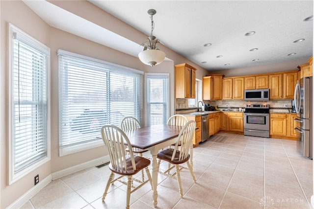 kitchen featuring decorative backsplash, stainless steel appliances, sink, light tile patterned floors, and decorative light fixtures