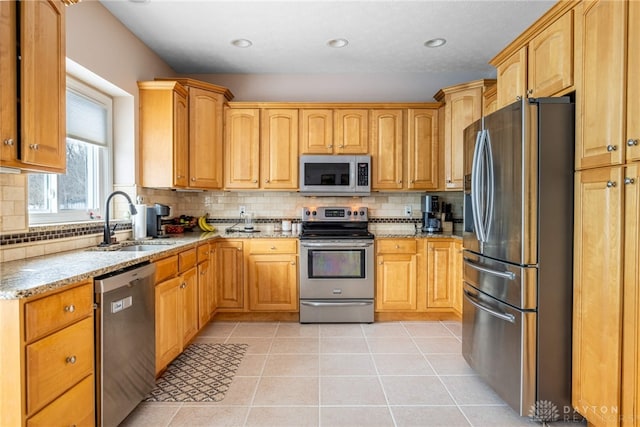 kitchen featuring tasteful backsplash, light stone countertops, sink, and appliances with stainless steel finishes