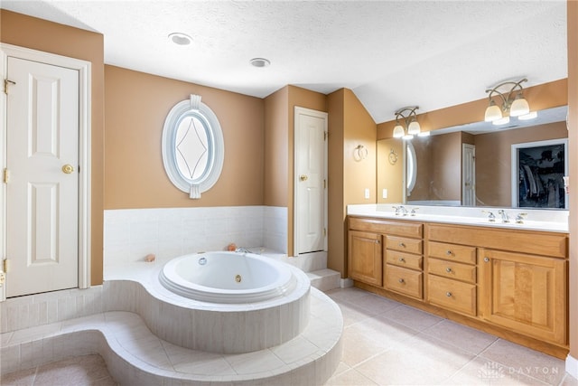 bathroom featuring tile patterned floors, vanity, a textured ceiling, vaulted ceiling, and tiled tub