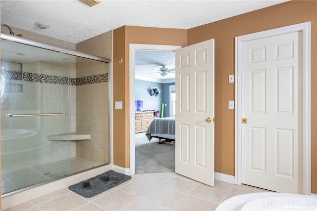 bathroom with tile patterned floors, ceiling fan, a shower with shower door, and a textured ceiling