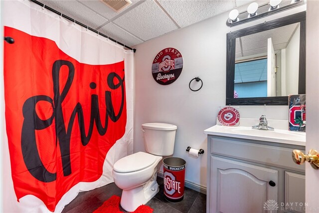 bathroom featuring a drop ceiling, vanity, tile patterned flooring, toilet, and curtained shower