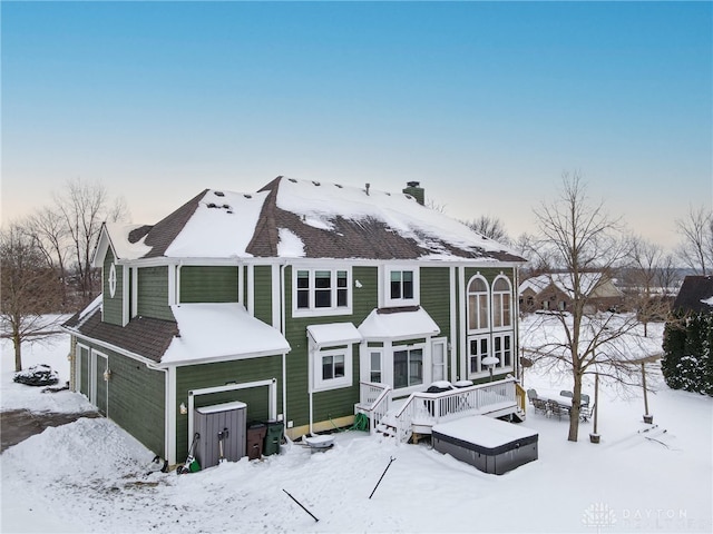 snow covered back of property featuring a wooden deck