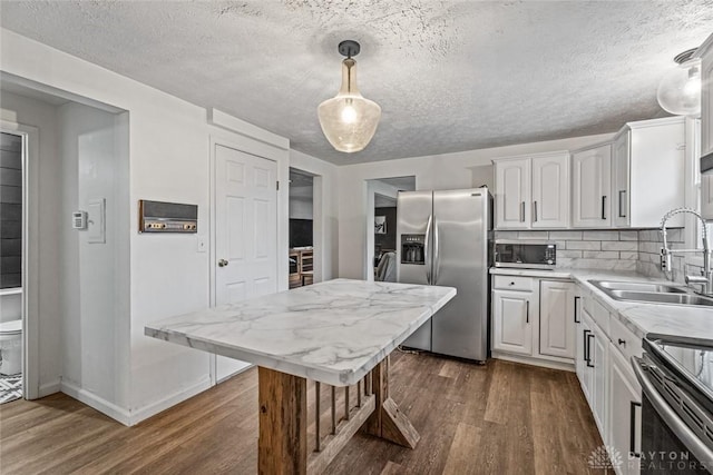 kitchen with stainless steel appliances, hanging light fixtures, dark wood-type flooring, white cabinets, and a sink